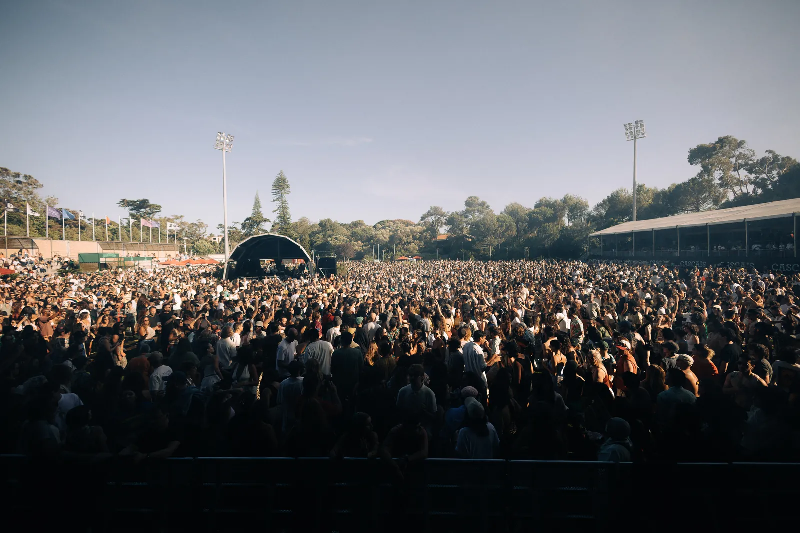 Público em festa junto ao palco ao pôr do sol